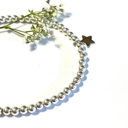 Pulsera elástica de bolitas de plata con estrella mini.