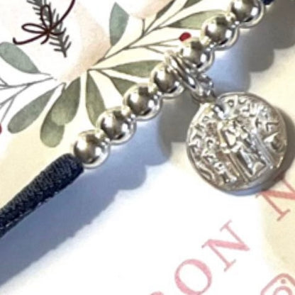 Pulsera con cinta elástica de seda con medalla religiosa.