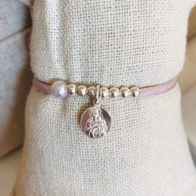 Pulsera elástica con bolitas de plata y escapulario.